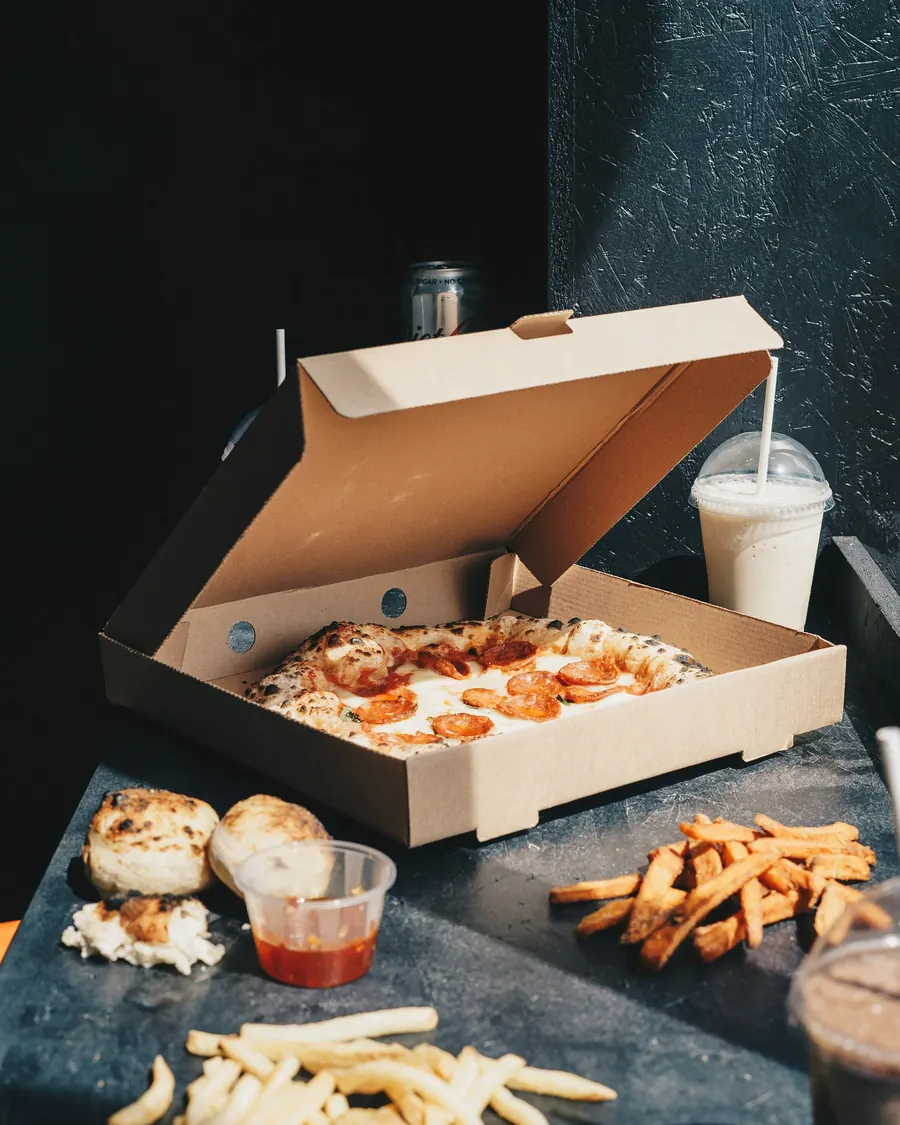 Open pizza box with snacks on a dark table